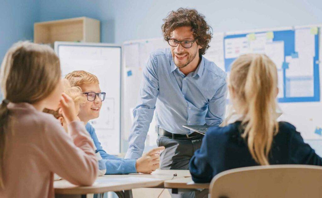 Engagierter junger Lehrer betreut Kinder im Unterricht – Stellenangebote für Lehrer in Dresden