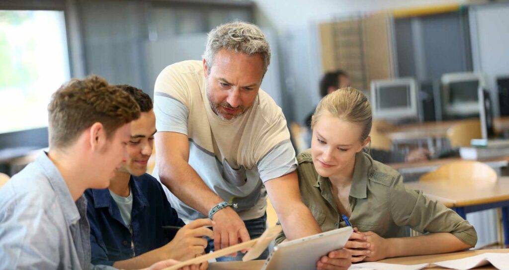 Lehrer erklärt Schülerinnen und Schülern etwas an einem Tablet in der HOGA Schule Dresden