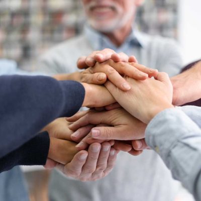 Team legt die Hände zusammen und zeigt Teamgeist – Zusammenarbeit und Jobs in Dresden